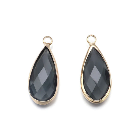 Teardrop-shaped black gemstones with gold settings on a white background