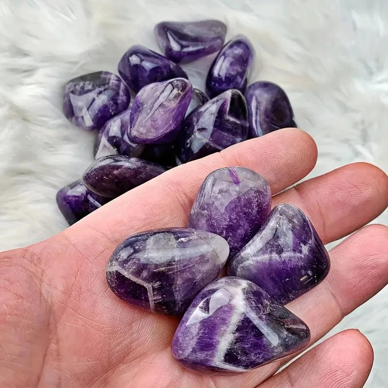 Purple amethyst crystals on a hand and white fluffy background