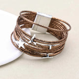 Brown leather bracelet with silver star and moon charms on a beige background