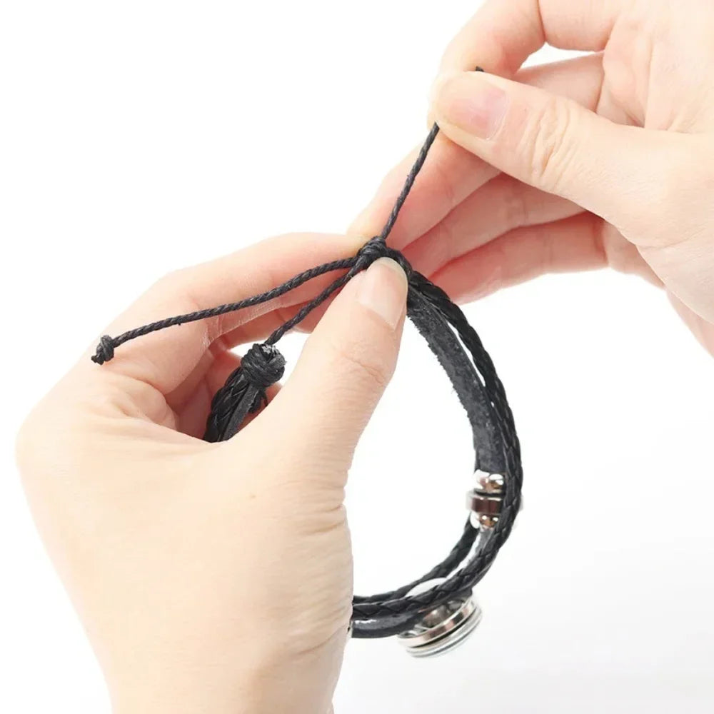 Close-up of hands tying a black cord around a bracelet on a white background