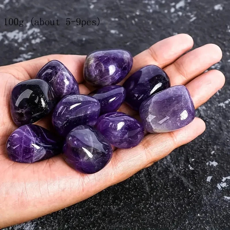 Hand holding purple amethyst crystals on a dark surface