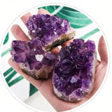 Hand holding three purple amethyst crystals against a green and white striped background