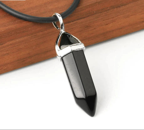 Black crystal pendant necklace on a wooden surface with a white background