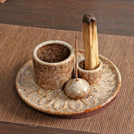 Ceramic tea set with a bowl, spoon, and whisk on a decorative plate.