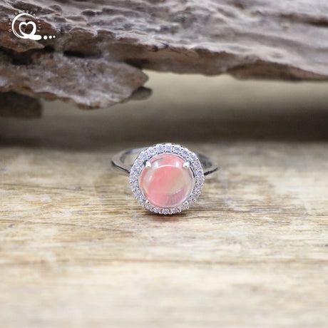 Silver ring with a pink gemstone on a wooden surface