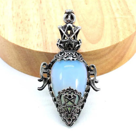 Decorative pendant with blue stone and silver intricate design on a white background