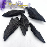 Black wing-shaped stones on a white surface with purple flowers in the background