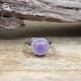 Silver ring with a purple gemstone on a wooden surface