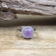 Silver ring with a purple gemstone on a wooden surface