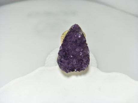 Amethyst crystal ring on a white stand with a blurred background