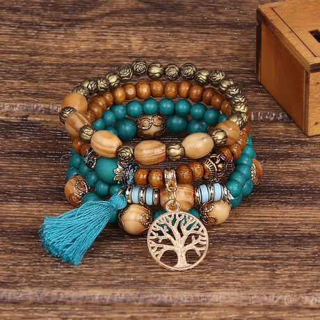 Stack of beaded bracelets with tree of life charm on a wooden surface