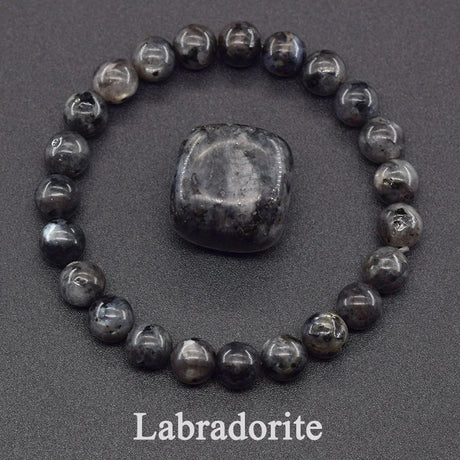 Labradorite stone with a bracelet made of similar stones on a dark background