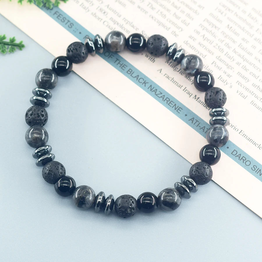 Black beaded bracelet on a light blue surface with text in the background