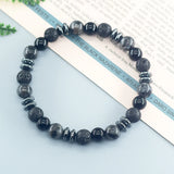 Black beaded bracelet on a light blue surface with text in the background