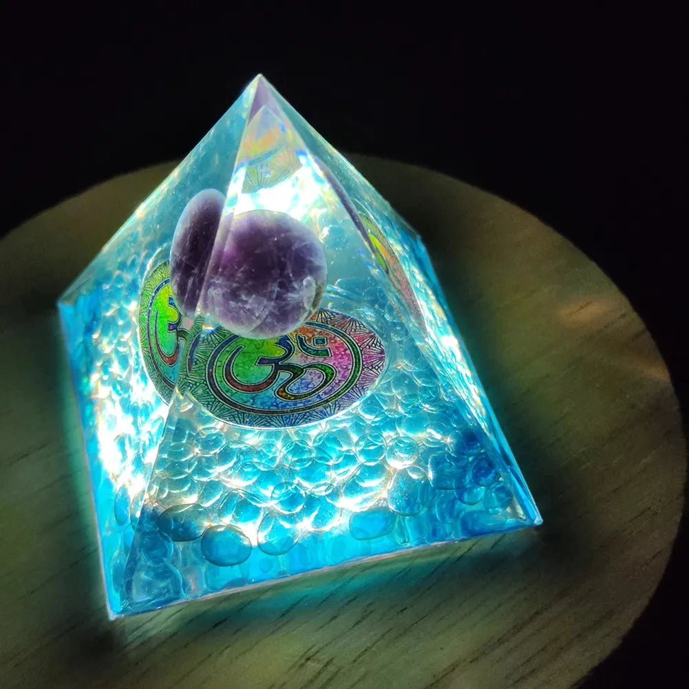 Crystal pyramid with a colorful Om symbol on a wooden surface