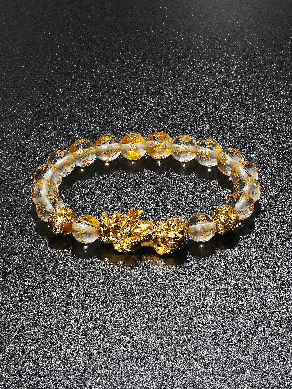 Bracelet with gold dragon clasp and clear beads on a dark background