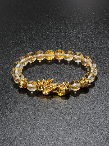 Bracelet with gold dragon clasp and clear beads on a dark background