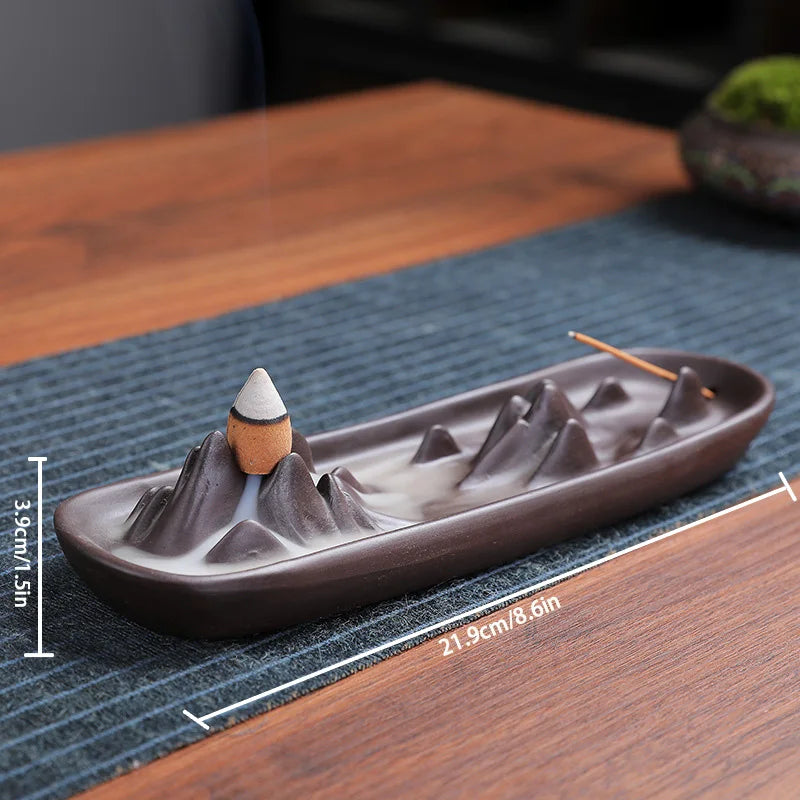 Ceramic incense burner with mountain design on a wooden surface