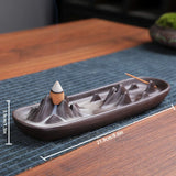 Ceramic incense burner with mountain design on a wooden surface