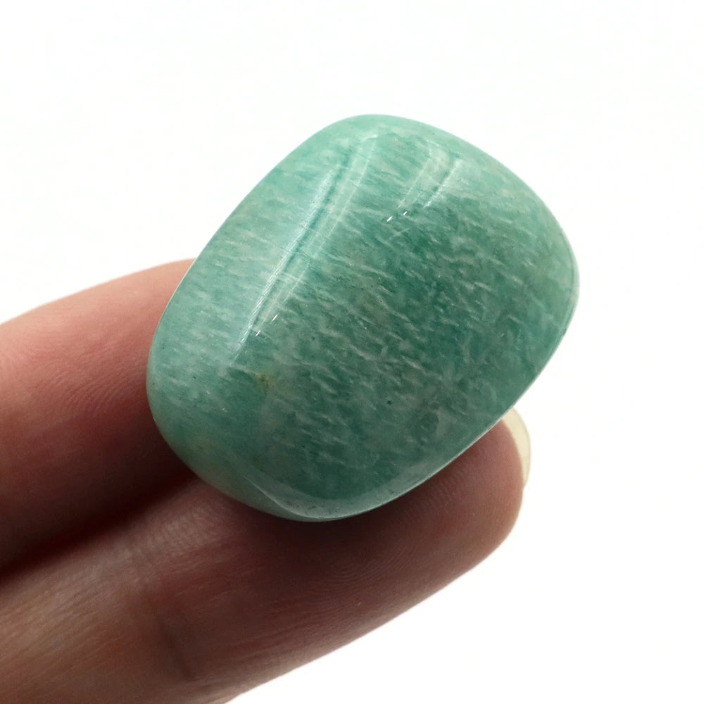 Green stone held between fingers on a white background