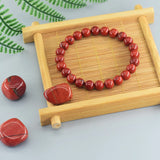 Red beaded bracelet on a wooden tray with a light background