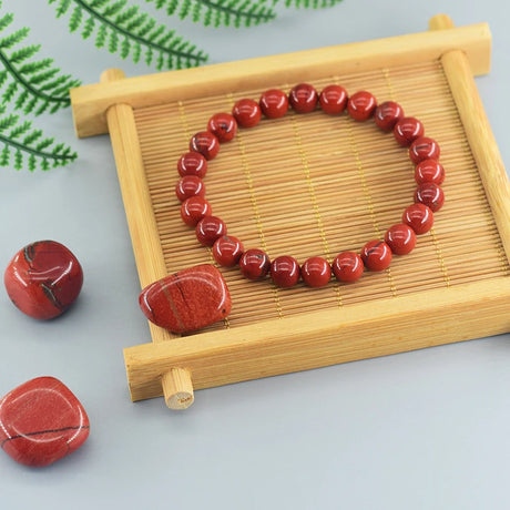 Red beaded bracelet on a wooden tray with a light background