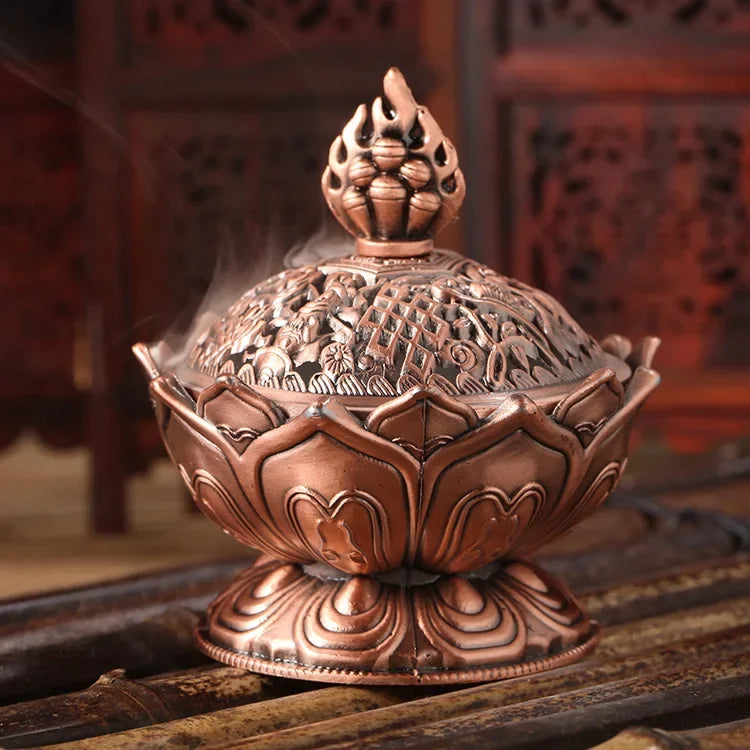 Decorative copper incense burner with intricate designs on a wooden surface.