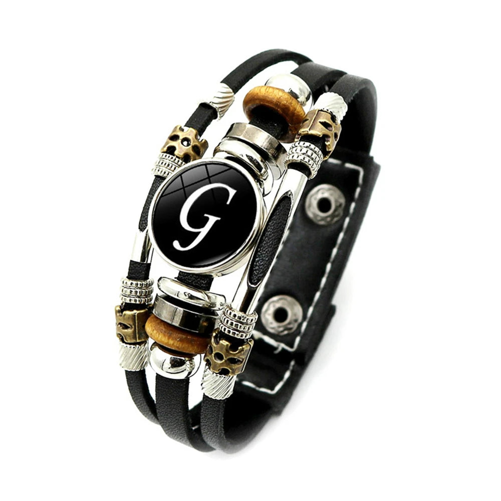 Black leather bracelet with decorative beads and a central black circle with a white 'G'.