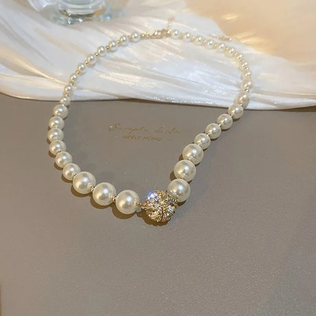 Pearl necklace with a gold clasp on a light fabric background