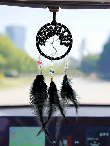 Car dashboard with a black feathered dreamcatcher ornament.