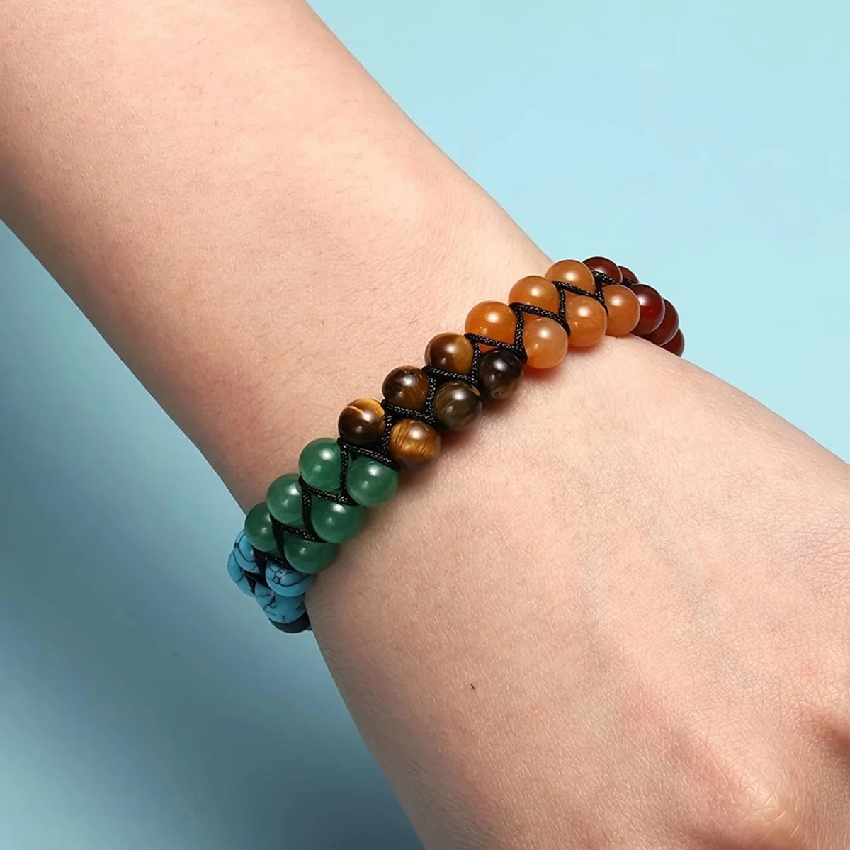 Multicolored beaded bracelet on a wrist with a light blue background