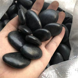 Hand holding a handful of black stones with a blurred background