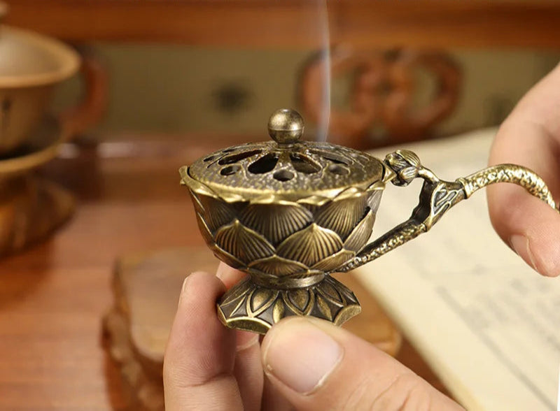 Bronze incense burner held by a hand with text overlay