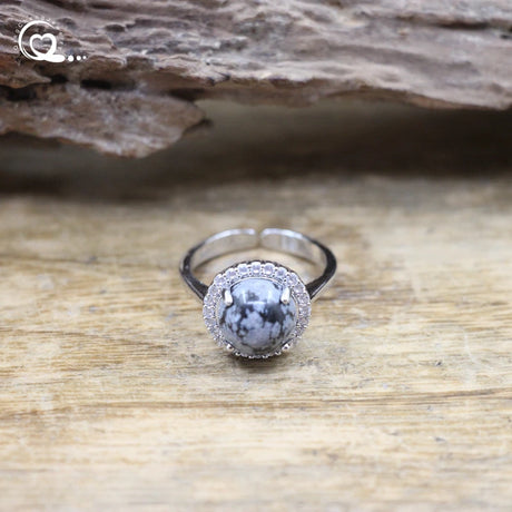 Silver ring with a central stone on a wooden surface