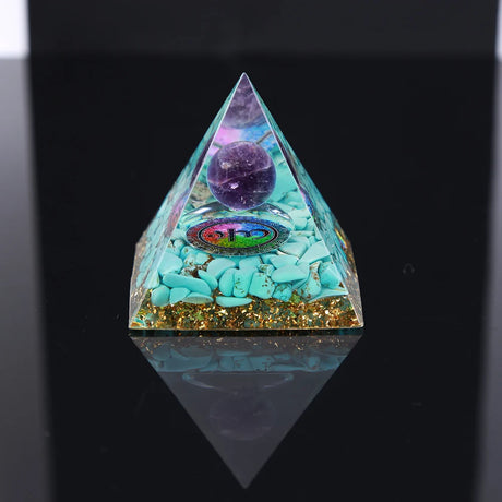 Pyramid-shaped crystal with purple sphere and turquoise stones on a black background