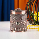 Decorative metal diffuser with intricate designs on a white surface.
