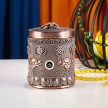 Decorative metal diffuser with intricate designs on a white surface.