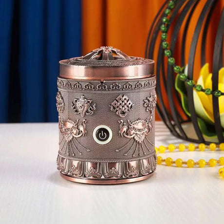 Decorative metal diffuser with intricate designs on a white surface.