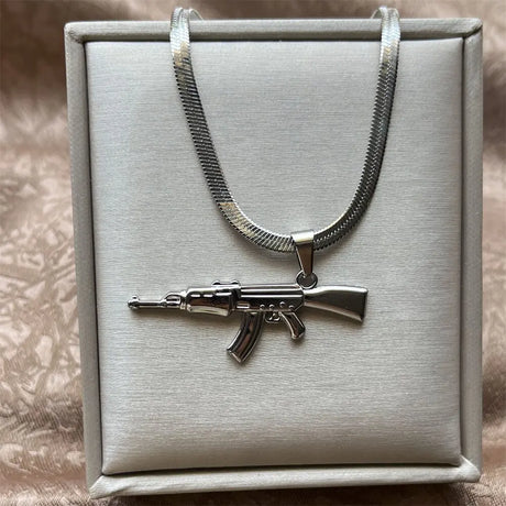 Silver rifle pendant necklace on a gray box