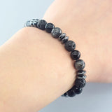 Black beaded bracelet on a wrist against a light background