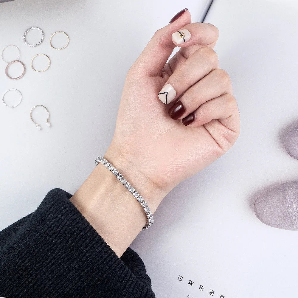 Hand wearing a bracelet with earrings displayed on a white background