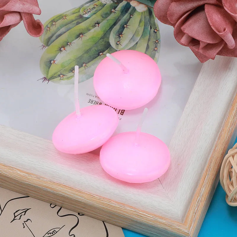Pink floating candles on a decorative surface with a cactus illustration and pink flowers.