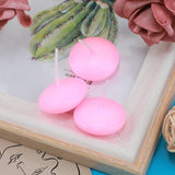 Pink floating candles on a decorative surface with a cactus illustration and pink flowers.
