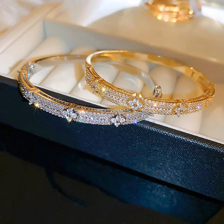 Gold bangles with diamond accents on a reflective surface