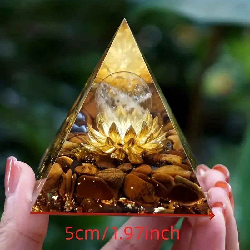 Triangular pyramid with a decorative item inside, held by hands against a blurred green background