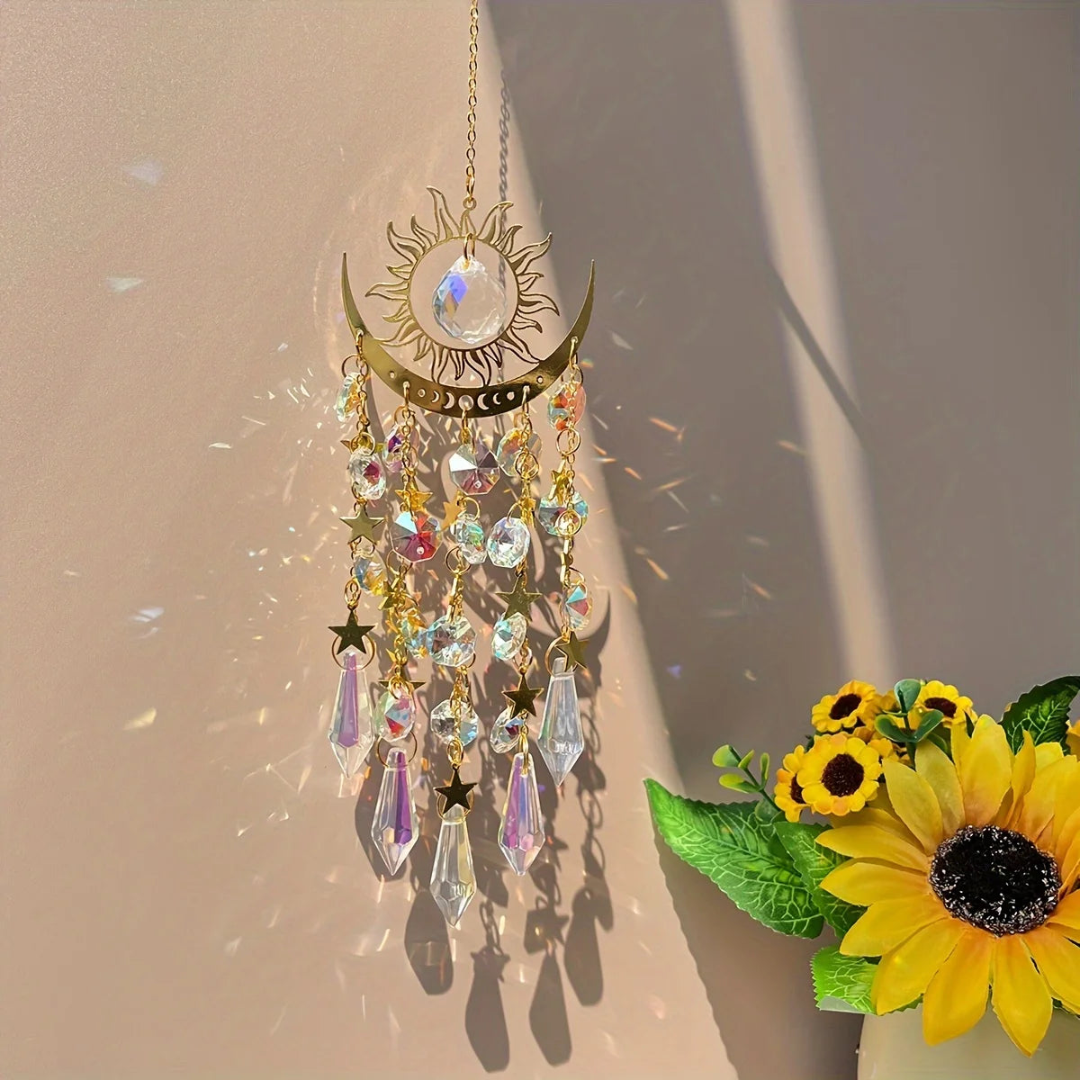 Decorative sun and moon hanging ornament with crystals and flowers on a neutral background