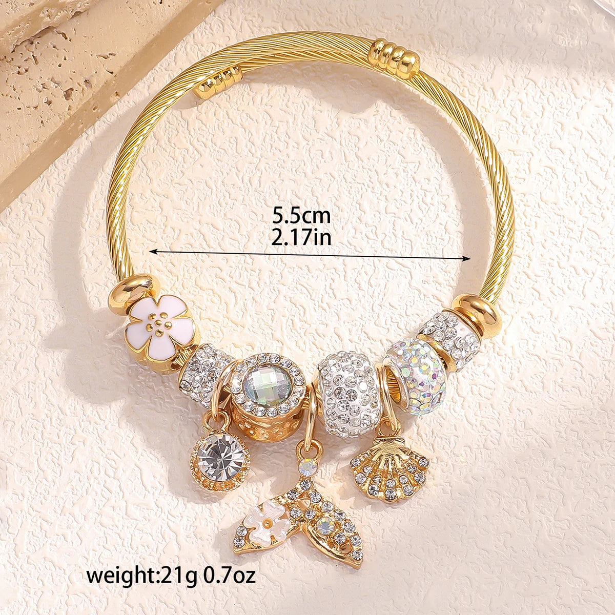 Gold bracelet with charms on a textured beige background