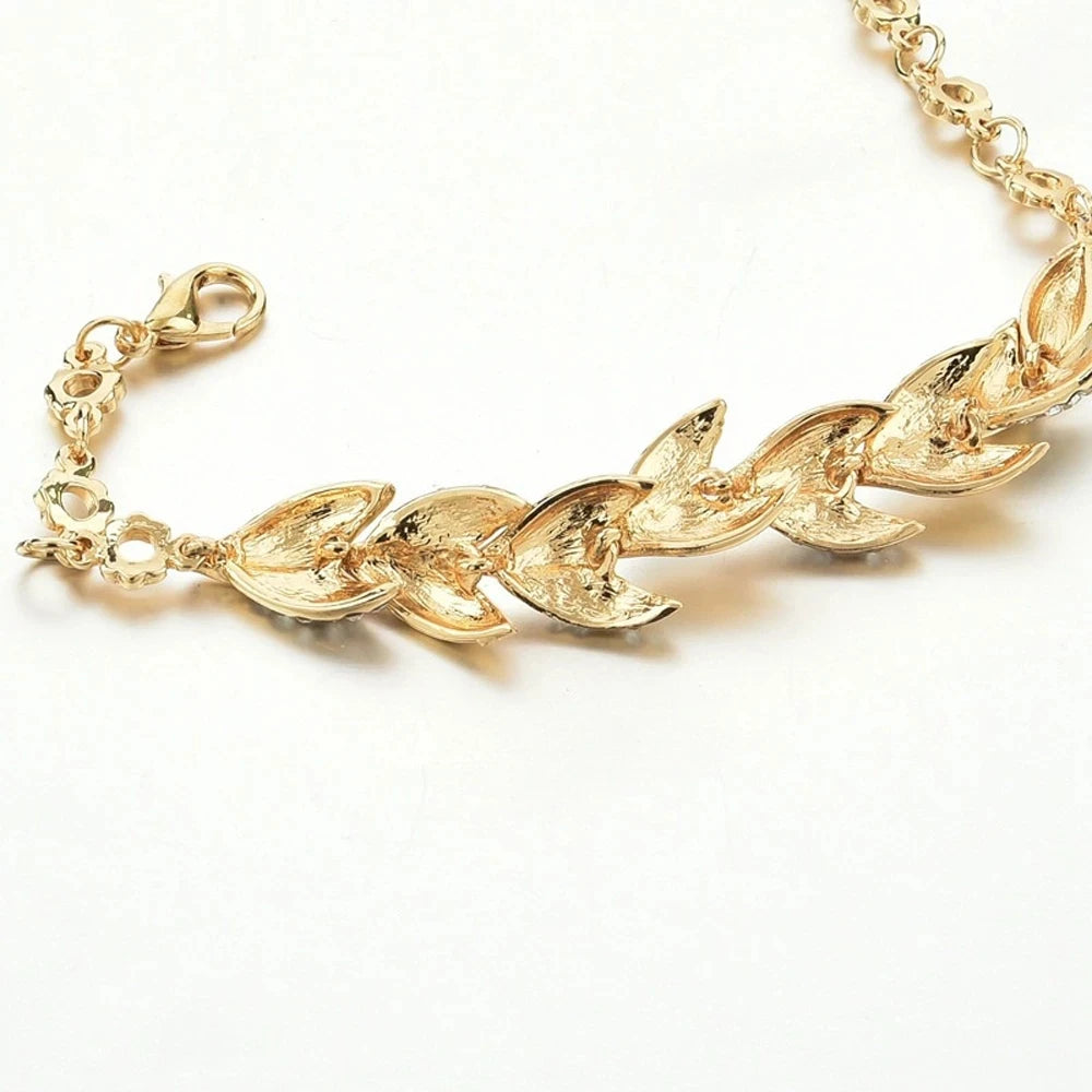 Gold bracelet with leaf-like links on a white background