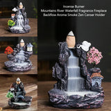 Decorative incense burner with waterfalls and buildings on a wooden surface.