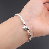 Silver bracelet on a wrist against a dark background